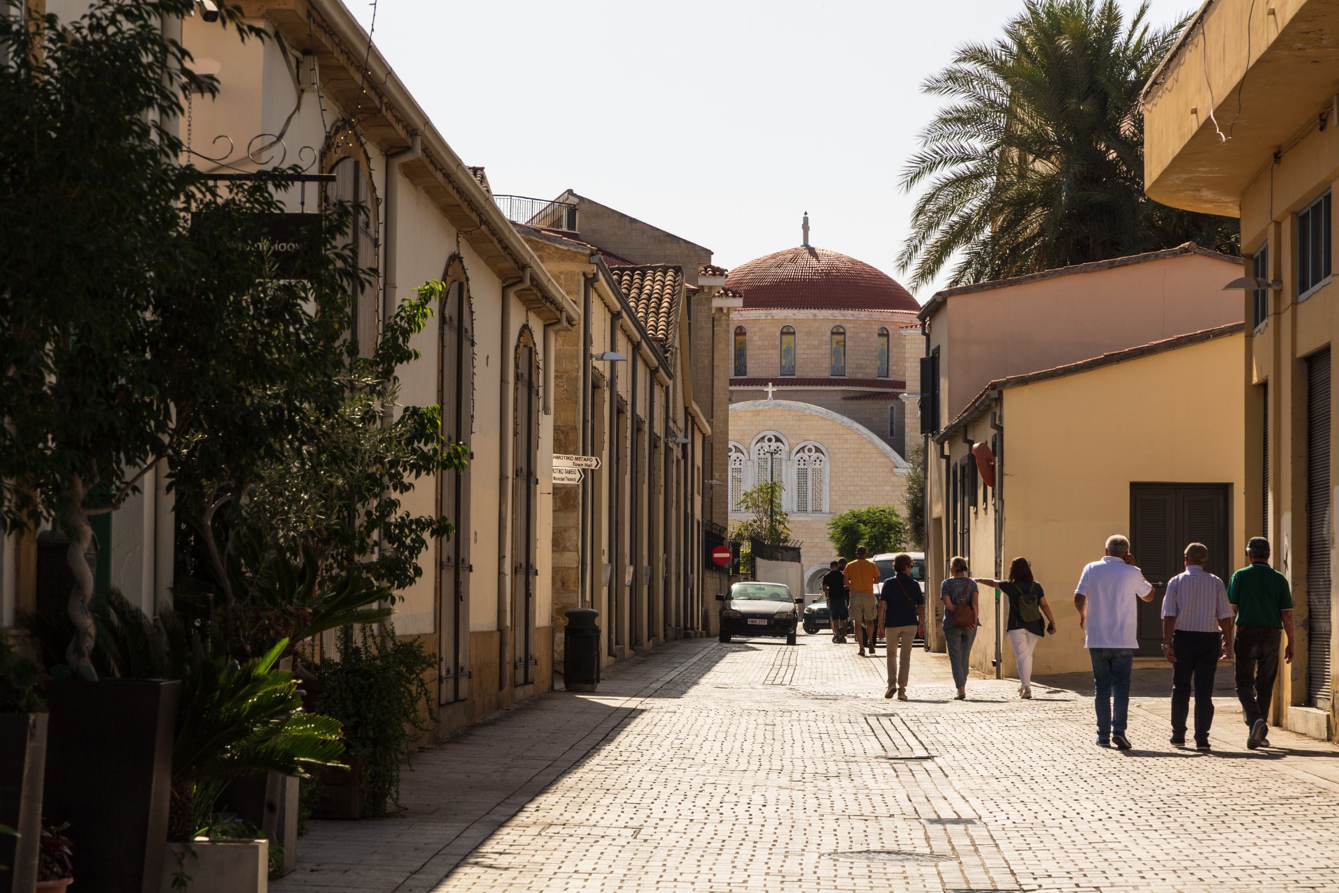 People walking along a narrow old town street in Nicosia towards a domed cathedral